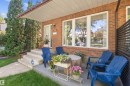 Brick exterior with a covered front porch featuring composite decking, multi-pane windows, and a privacy screen - 10940 123 Street, Edmonton, AB 