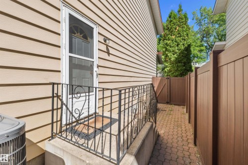 Side entry with a storm door, wrought iron railing, and a paver pathway - 10940 123 Street, Edmonton, AB 