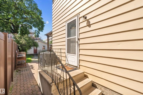 Cream-colored siding exterior featuring a white storm door - 10940 123 Street, Edmonton, AB 