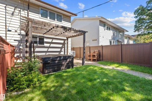 Expansive backyard featuring a manicured lawn, a concrete paver pathway, and a privacy fence - 10940 123 Street, Edmonton, AB 