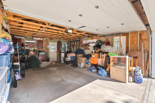 Spacious garage with concrete flooring, exposed wood beam ceiling, and a white paneled overhead door - 10940 123 Street, Edmonton, AB 