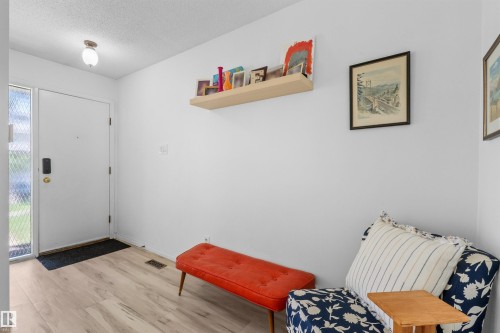 Entryway featuring wood-finish flooring, a white entry door with patterned glass sidelight, and a ceiling-mounted light fixture - 10940 123 Street, Edmonton, AB 