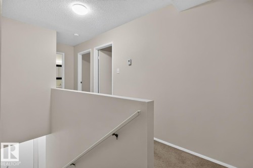 Upper-level hallway featuring neutral wall paint, white trim, and carpeted flooring - 106 237 Woodvale Road W, Edmonton, AB 