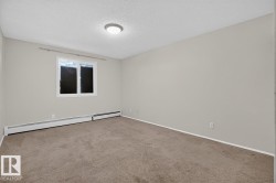 Carpeted room featuring light gray walls, a window with white trim, and baseboard heating units - 