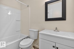 Bathroom featuring a white vanity with integrated sink, chrome faucet, and rectangular black-framed mirror - 