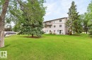 Expansive green space featuring a multi-story building, mature trees, and a paved parking area - 106 237 Woodvale Road W, Edmonton, AB 