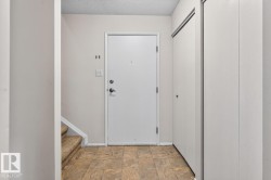 Entryway featuring patterned tile flooring, a white entry door with dark hardware, and a sliding closet system - 