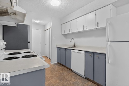 Kitchen featuring two-tone cabinetry with white upper and blue-gray lower cabinets, a white electric range, and a white refrigerator - 106 237 Woodvale Road W, Edmonton, AB 