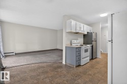 Kitchen area featuring tile flooring, white upper cabinetry, blue lower cabinetry, a white electric range, and a stainless steel refrigerator - 