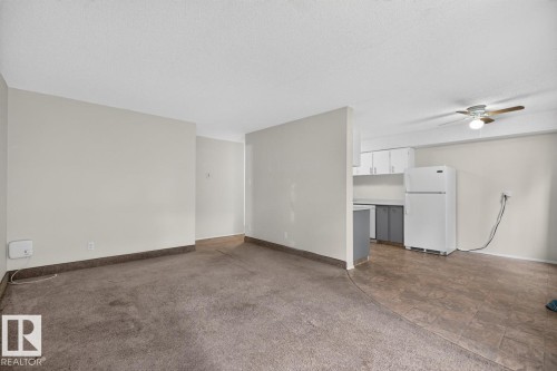 Living area featuring carpet flooring, light-toned walls, and a partial wall separating the kitchen - 106 237 Woodvale Road W, Edmonton, AB 