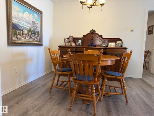 Dining area featuring wood-finish flooring, light-colored walls, and a classic chandelier - 102 10903 21 Avenue, Edmonton, AB - Indoor Photo Showing Dining Room