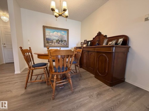 Dining area featuring wood-finish flooring and a contemporary brass chandelier - 102 10903 21 Avenue, Edmonton, AB - Indoor Photo Showing Dining Room