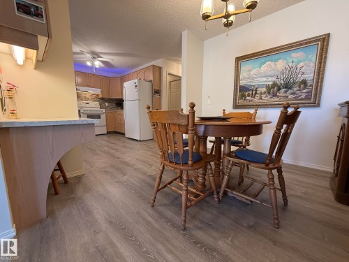 Open-concept living space featuring wood-finish flooring, a kitchen with light wood cabinetry and white appliances, and a dining area - 102 10903 21 Avenue, Edmonton, AB - Indoor Photo Showing Dining Room