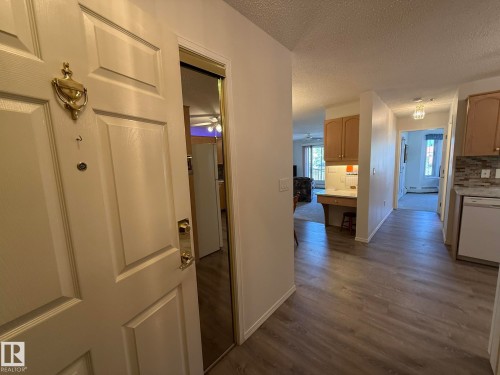 Entryway featuring wood-finish flooring, a mirrored closet door, and a built-in desk area - 102 10903 21 Avenue, Edmonton, AB - Indoor Photo Showing Kitchen