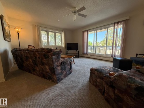 Living area featuring expansive sliding glass doors and a ceiling fan - 102 10903 21 Avenue, Edmonton, AB - Indoor Photo Showing Living Room