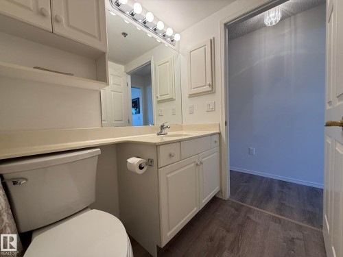 Bathroom featuring a vanity with a light-colored countertop, white cabinetry, and a full-width mirror - 102 10903 21 Avenue, Edmonton, AB - Indoor Photo Showing Bathroom