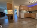 Kitchen featuring light wood-finish cabinetry, a patterned tile backsplash, a built-in dishwasher, and wood-finish flooring - 102 10903 21 Avenue, Edmonton, AB  - Indoor Photo Showing Kitchen 