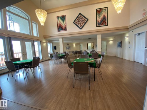 Spacious common area featuring high ceilings, wood-finish flooring, and ample natural light from large windows and double glass doors - 102 10903 21 Avenue, Edmonton, AB - Indoor Photo Showing Dining Room