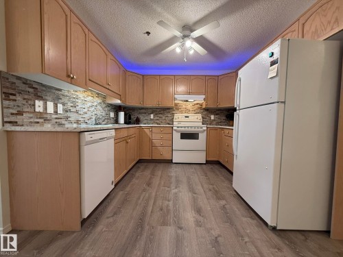 Kitchen featuring wood-finish cabinetry, mosaic tile backsplash, and wood-finish flooring - 102 10903 21 Avenue, Edmonton, AB - Indoor Photo Showing Kitchen