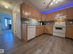 Kitchen featuring wood-finish cabinetry, white appliances, a mosaic tile backsplash, and light-toned countertops - 