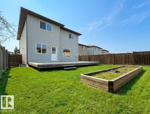 Expansive backyard featuring a large wooden deck, a dedicated garden bed, and a full perimeter wood fence - 1919 Hammond Place, Edmonton, AB 
