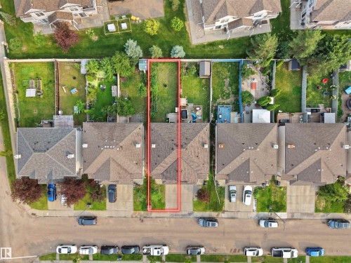 Aerial perspective highlighting the property outlined in red, featuring a rectangular lot with green space - 8111 7 Avenue Sw, Edmonton, AB 