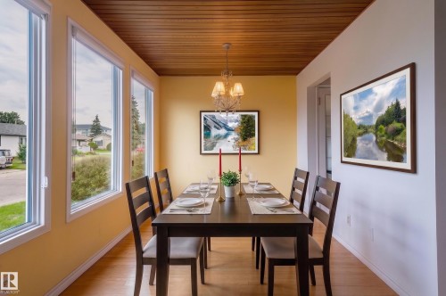 Dining space featuring expansive picture windows, wood-finish flooring, a wood-paneled ceiling, and a chandelier lighting fixture - 11415 142 Avenue, Edmonton, AB 