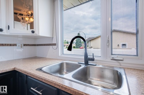 Double basin stainless steel sink with a matte black high-arc faucet, set within a speckled countertop - 11415 142 Avenue, Edmonton, AB 