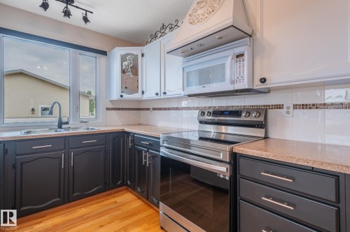 Kitchen featuring dual-toned cabinetry, a stainless steel range, and a built-in microwave - 11415 142 Avenue, Edmonton, AB 