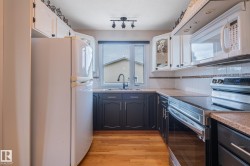 Kitchen featuring light wood-finish flooring, white upper cabinetry, and dark lower cabinetry - 