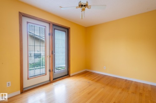 Room featuring wood-finish flooring, white baseboards, and a ceiling fan with integrated lighting - 11415 142 Avenue, Edmonton, AB 