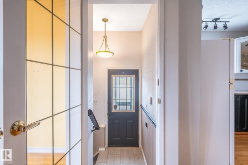 Entryway featuring a dark paneled door with glass inserts, overhead pendant lighting, and wood-finish flooring - 11415 142 Avenue, Edmonton, AB 