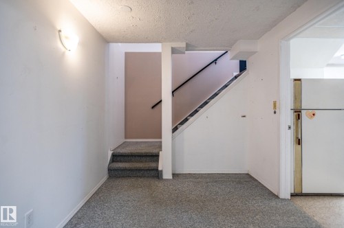 Carpeted staircase with dark handrail - 11415 142 Avenue, Edmonton, AB 