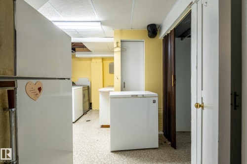 Utility space featuring vinyl flooring, drop ceiling, and a white interior door with a brass knob - 11415 142 Avenue, Edmonton, AB 