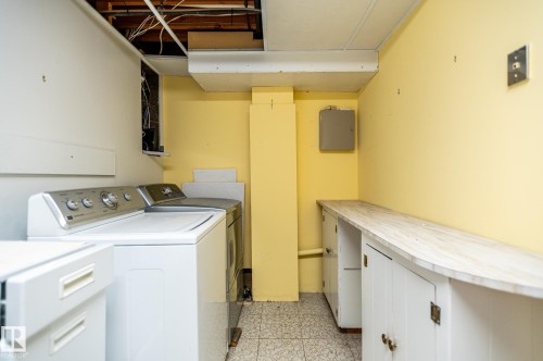 Dedicated laundry area featuring a tile floor, white built-in cabinetry, and an extended countertop space - 11415 142 Avenue, Edmonton, AB 