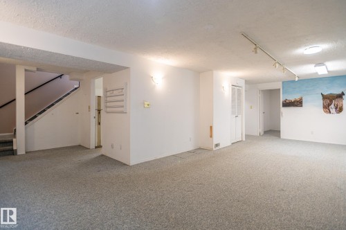 Spacious carpeted room featuring track lighting and a ceiling-mounted light fixture - 11415 142 Avenue, Edmonton, AB 