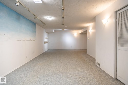Spacious room featuring light-colored carpeting, track lighting, and multiple wall sconces - 11415 142 Avenue, Edmonton, AB 