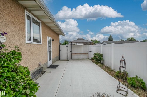 Expansive concrete patio bordered by a white privacy fence - 11415 142 Avenue, Edmonton, AB 
