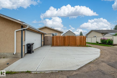 Concrete driveway leading to an attached single-car garage with a white overhead door - 11415 142 Avenue, Edmonton, AB 