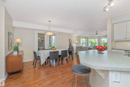 Open-concept dining area with wood-finish flooring, a contemporary chandelier, and French doors - 130 9008 99 Avenue Nw, Edmonton, AB 