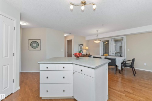 Kitchen island with white cabinetry and light-toned countertop - 130 9008 99 Avenue Nw, Edmonton, AB 