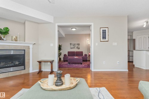 Hardwood-finish flooring throughout, featuring a fireplace with a tiled surround and white mantel - 130 9008 99 Avenue Nw, Edmonton, AB 