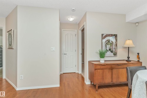 Hardwood flooring throughout a hall area with light-toned walls and white trim - 130 9008 99 Avenue Nw, Edmonton, AB 