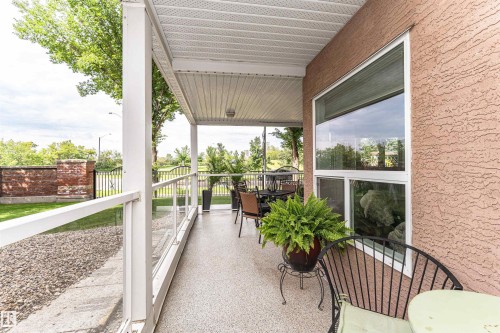 Covered patio featuring a textured exterior, glass railing, and durable composite flooring - 130 9008 99 Avenue Nw, Edmonton, AB 