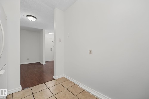 Foyer featuring light-toned square tile flooring, white baseboards, and a neutral wall palette - #6E 11608 28 Av Nw Nw, Edmonton, AB - Indoor Photo Showing Other Room