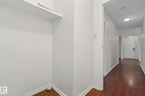Hallway featuring wood-finish flooring, white walls, and built-in overhead lighting - #6E 11608 28 Av Nw Nw, Edmonton, AB - Indoor