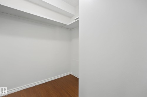 Walk-in closet featuring wood-finish flooring, white walls, and built-in shelving - #6E 11608 28 Av Nw Nw, Edmonton, AB - Indoor