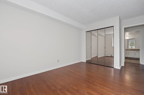 Room featuring wood-finish flooring, white baseboards, and neutral wall paint - #6E 11608 28 Av Nw Nw, Edmonton, AB - Indoor Photo Showing Other Room
