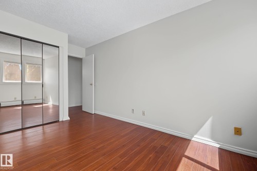 Spacious room featuring wood-finish flooring, light-toned walls, and white trim - #6E 11608 28 Av Nw Nw, Edmonton, AB - Indoor Photo Showing Other Room