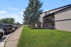 Multi-story residential building featuring horizontal siding, dark trim, and individual balconies with black railings - 